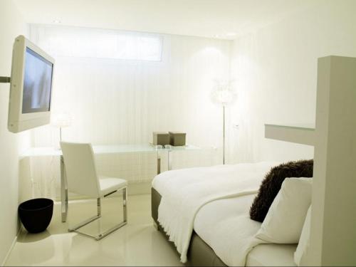 a white bedroom with a bed and a chair and a tv at VISIONAPARTMENTS Binzmühlestrasse 50 - contactless check-in in Zürich