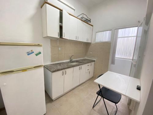 een keuken met een witte koelkast en een tafel bij Hashoeva Living Residence in Tel Aviv