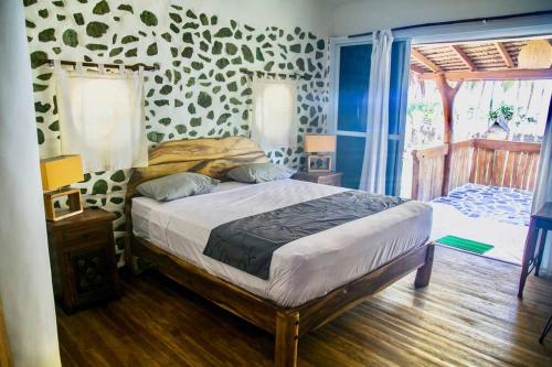 1 dormitorio con 1 cama en una habitación con una pared con estampado animal en Beach-Front Sumbawa Surf House en Lemonga