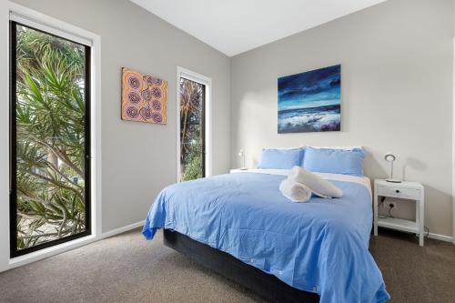 una camera con un letto blu e due finestre di Serenity at Smiths Beach a Smiths Beach