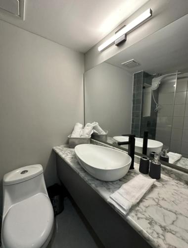 a bathroom with a sink and a toilet and a mirror at Lujoso y cómodo apartamento in Tegucigalpa
