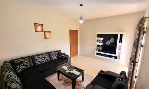 a living room with a black couch and a tv at Vila Dean in Berat