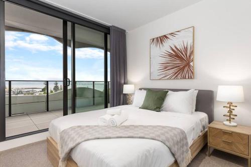 a bedroom with a large bed and a balcony at Sea View 2BR w Best Rooftop Pool in Melb! in Melbourne
