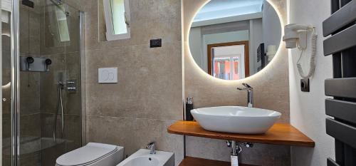 a bathroom with a sink and a toilet and a mirror at Casa Guarnati Lake View Apartments in Malcesine