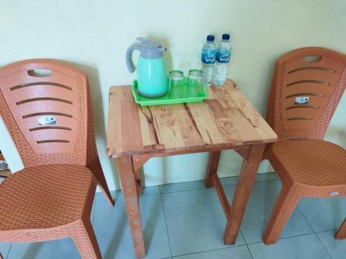 una mesa de madera con 2 sillas y una jarra. en Kempu Tigan, en Berastagi