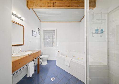un bagno con vasca, lavandino e WC di North Lodge Highland Cottage a Pokolbin