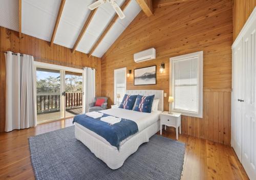 a bedroom with a large bed and wooden walls at North Lodge Highland Cottage in Pokolbin