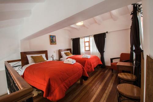 um quarto com 2 camas com lençóis vermelhos e uma cadeira em Wilkamayu Hotel em Sicuani