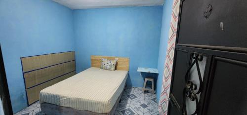 a small bedroom with a bed and a blue wall at Jaguar long-stay Guest House in Ciudad Vieja in Ciudad Vieja