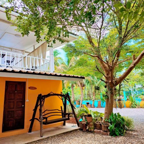 a playground in front of a house with a tree at PRAKAI RESORT in Ban Don Klang