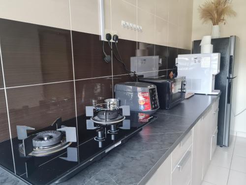a kitchen with a black counter top with appliances on it at UniVilla- Ideal Family Home for 18pax in Gelugor