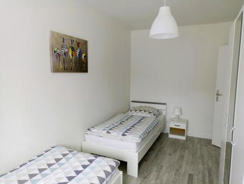 バート・ファリングボステルにあるFerienhaus Heideのベッドルーム1室(ベッド2台付)が備わります。壁には絵画が飾られています。