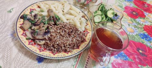 a plate of food with meat and pasta and a drink at 锦江LoveMyHome in Almaty
