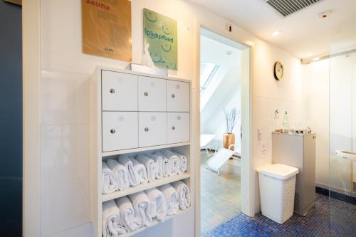 a bathroom with a toilet and a shelf with towels at Novum Hotel Imperial Frankfurt Messe in Frankfurt/Main