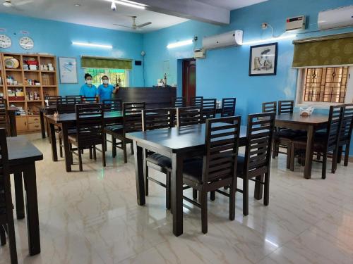 un comedor con mesas, sillas y un piano en 소문난게스트하우스, en Kanchipuram