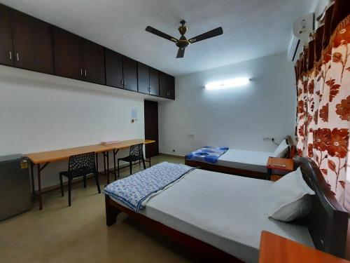 1 dormitorio con 2 camas, escritorio y ventilador de techo en 소문난게스트하우스, en Kanchipuram