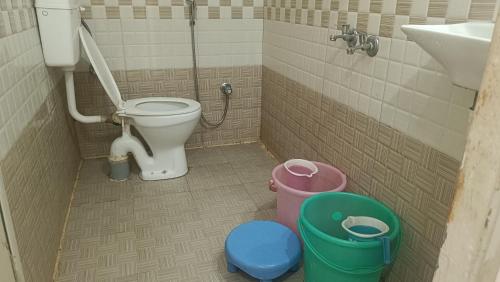 a bathroom with a toilet and a sink and buckets at Samarth home`stay in Pachmarhī