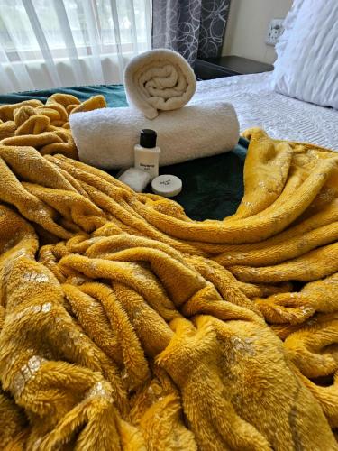 a yellow blanket with a towel and a roll of towels on a bed at Adante Lodge & Conferencing in Mthatha