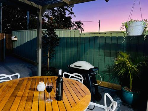 uma mesa com copos de vinho e um grelhador no pátio em 2Bays Studio- Walk to 2 Beaches! Perfect Location with Private Courtyard & BBQ em Nelson Bay
