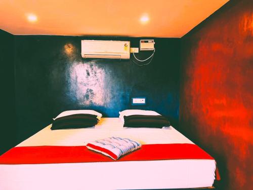 Nature Zone Resort في بونديتْشيري: غرفة نوم بسرير احمر وبيض مع مروحة