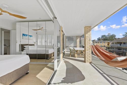 um quarto com uma cama e uma rede de descanso numa varanda em Stunning 2-Bed Coastal Pad Across From the Beach em Sydney