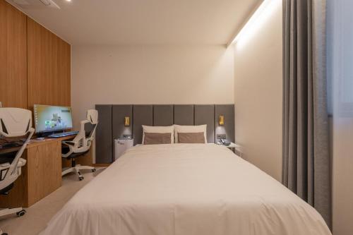 a bedroom with a bed and a desk and a computer at H-avenue Hotel Munhyeon in Busan