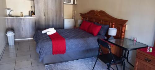a bedroom with a bed with red pillows and a table at DeLutz Overnight Room 3 in Polokwane