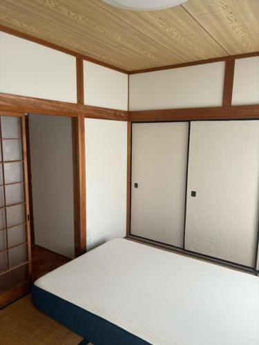 a room with a bed with four sliding glass doors at 高知県　みどりの家 in Gomen