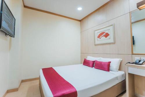 a bedroom with a white bed with red pillows at Hotel 81 Fuji in Singapore