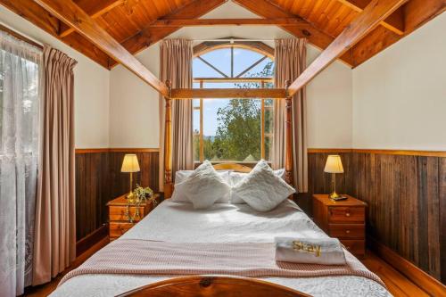 een slaapkamer met een bed en een groot raam bij StayAU The Loft 1BR Rustic Picturesque Cottage in Badger Creek