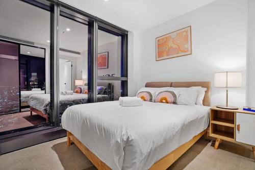a bedroom with a large white bed and a window at Lv 60 Skyline 2B 2B 1CP in Heart of Melbourne in Melbourne