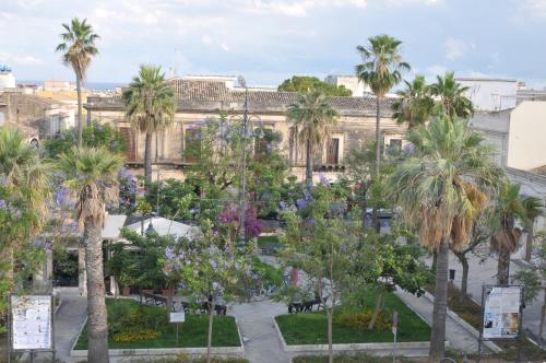 a view of a park with palm trees and a building at Morfeo Charming Rooms & Relax in Avola