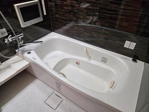 a white bath tub in a bathroom with a computer at 夢街道53 in Okayama