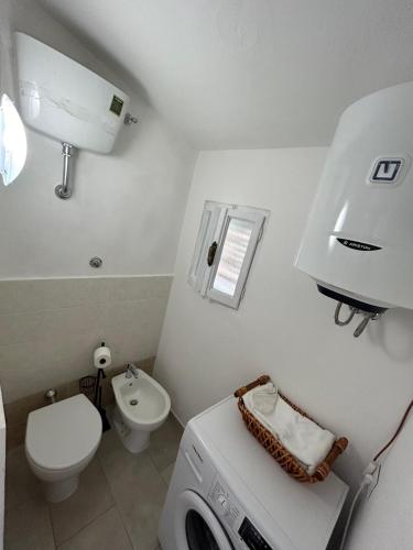 a bathroom with a washing machine and a toilet at Aura Entis in Canino
