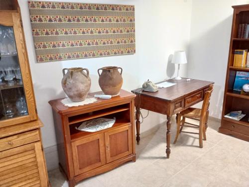 Habitación con escritorio y mesa con jarrones. en CASA FIGUS Via Roma 20 Narbolia, en Narbolia