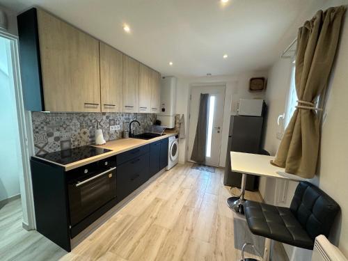 une cuisine avec des armoires noires et un plancher en bois dans l'établissement CARPE DIEM, à Sète