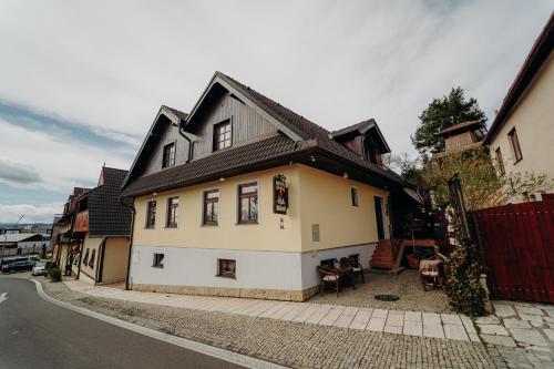 a white house with a black roof on a street at Penzion Alžbetka in Poprad