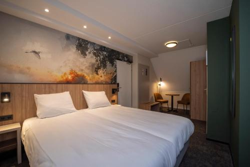 Fletcher Hotel Restaurant Rooland في آرسين: غرفة نوم بسرير ابيض ولوحة على الحائط