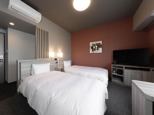 ein Hotelzimmer mit 2 Betten und einem Flachbild-TV in der Unterkunft Hotel Route Inn Kyoto Kameoka in Kameoka