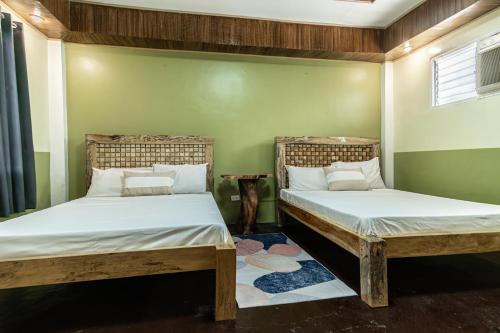 One Alo Hotel and Resort في Manaoag: سريرين في غرفة بجدران خضراء