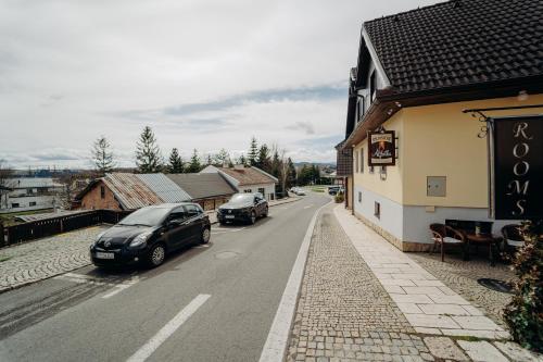 two cars parked on a street next to a building at Penzion Alžbetka in Poprad