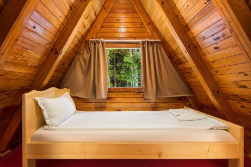 a bed in a wooden room with a window at Chalet Musala Borovets by BookVillaBG in Borovets