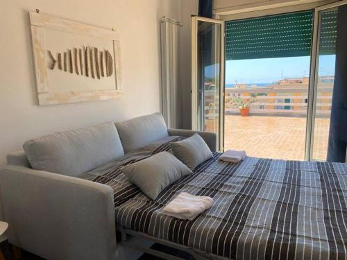 a bed in a room with a large window at La terrazza sul porto in Anzio