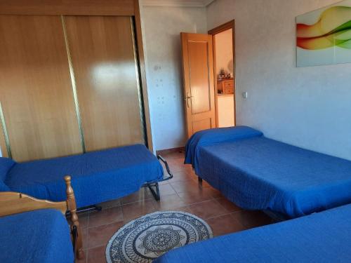 a room with two blue beds and a door at Shivanda, Habitaciones en Centro de Bienestar en la Naturaleza in Pioz