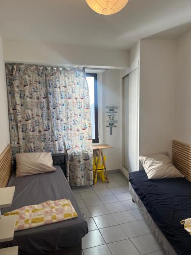 Cette chambre comprend 2 lits et un rideau. dans l'établissement The Building Canebière, à Marseille