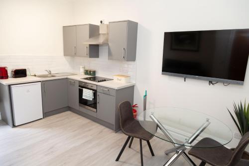 een keuken met een tv en een tafel en stoelen bij Unit 1 Island View Apartments - Town Centre Walk To Everything in Cobh