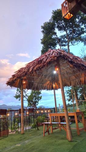 a picnic table with a straw umbrella and a bench at Puluong Bao Gia Homestay in Hương Bá Thước
