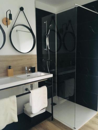 une salle de bain avec un lavabo et un miroir dans l'établissement Les Remparts, à Châteauneuf-du-Faou