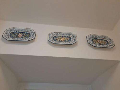 três pratos estão pendurados numa parede branca em Capraia per te em Ilha Capraia