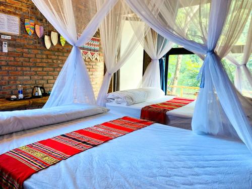 ein Schlafzimmer mit 2 Betten und Vorhängen darauf in der Unterkunft Pu Luong Riverside Lodge in Hương Bá Thước